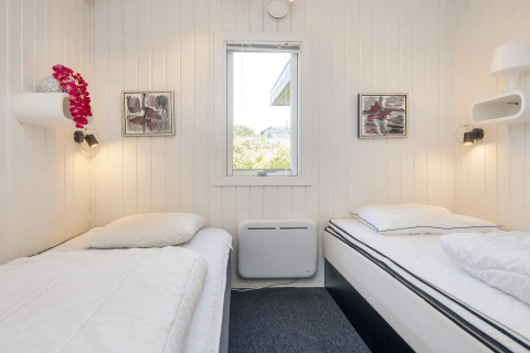 Helles Zimmer mit zwei Einzelbetten im Seaside Charm in Rindby, Dänemark, Fenster und moderner Wandkunst.
