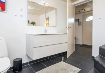 Modernes Badezimmer in Seaside Charm in Rindby, Dänemark, mit großem Spiegel und schwarzen Fliesen.