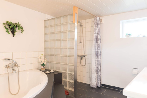 Modernes Badezimmer mit Badewanne, Dusche und Glassteinen in einer Lodge in Rindby, Dänemark.