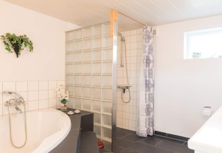 Modernes Badezimmer mit Badewanne, Dusche und Glassteinen in einer Lodge in Rindby, Dänemark.