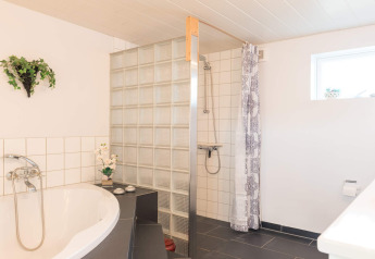 Modernes Badezimmer mit Badewanne, Dusche und Glassteinen in einer Lodge in Rindby, Dänemark.