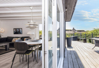 Helles Wohnzimmer und Holzterrasse in der Seaside Charm Lodge in Rindby, Dänemark, mit tollem Ausblick.
