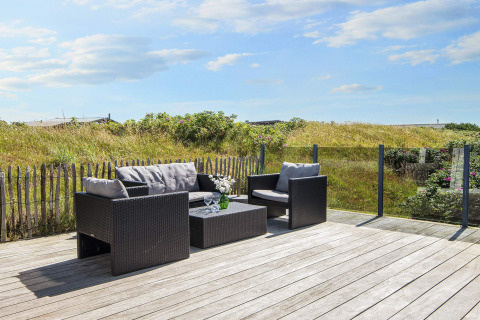 Holzterrasse mit modernen Gartenmöbeln und Glasgeländer bei Seaside Charm in Rindby, Dänemark.