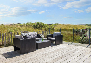 Holzterrasse mit modernen Gartenmöbeln und Glasgeländer bei Seaside Charm in Rindby, Dänemark.