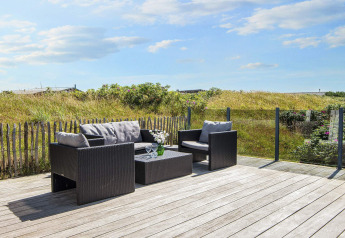 Holzterrasse mit modernen Gartenmöbeln und Glasgeländer bei Seaside Charm in Rindby, Dänemark.