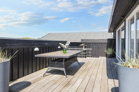 Holzterrasse mit schwarzem Zaun und modernem Gartentisch an der Seaside Charm Lodge in Rindby, Dänemark.