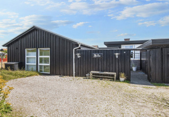 Außenansicht der Lodge Seaside Charm in Rindby, Dänemark, mit schwarzer Fassade und Kiesweg.