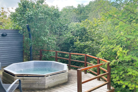 Vasca idromassaggio su terrazza in legno immersa nel verde presso una casa vacanze a Gränna, Svezia.
