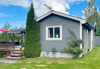 Buitenzicht op een 6-persoons vakantiehuis in Gränna, Zweden, met houten terras en groene tuin.