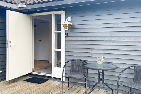 Buitenpatio van 6-persoons vakantiehuis in Gränna, Zweden, met tafeltje, twee stoelen en openstaande deur.