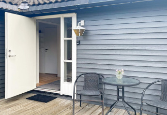 Terrasse eines 6-Personen-Ferienhauses in Gränna, Schweden, mit offenem Eingang, Tisch und Stühlen.