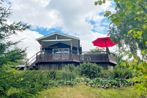 Ferienhaus für 6 Personen in GRÄNNA mit großer Holzterrasse, rotem Sonnenschirm und viel Grün.