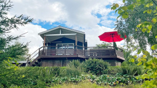 Casa vacanze per 6 persone a GRÄNNA con terrazza in legno, grande ombrellone rosso e molto verde.