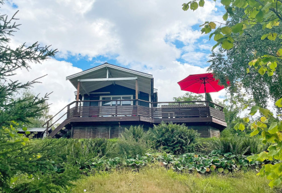 Casa vacanze per 6 persone a GRÄNNA con terrazza in legno, grande ombrellone rosso e molto verde.