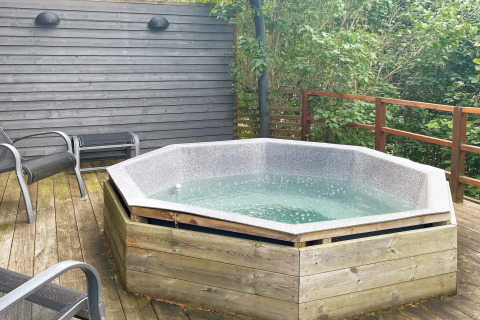 Vasca idromassaggio esterna su terrazza in legno presso una casa vacanza a Gränna, Svezia, con sedie arredate.
