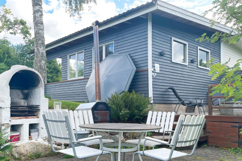 Buitenruimte met tafel, stoelen en barbecue aan een vakantiehuis in Gränna, Zweden.