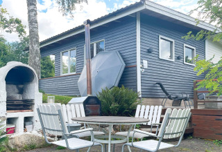 Gemütlicher Außenbereich mit Esstisch, Stühlen und Grill vor Ferienhaus in Gränna, Schweden.