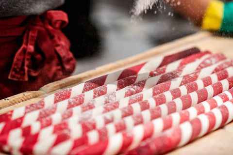Handgemaakte rood-witte zuurstokken worden bestrooid met suiker in een bakkerij in Gränna, Zweden.