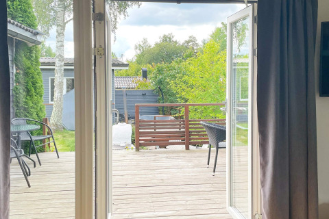 Vista dall'interno verso un terrazzo in legno con mobili da esterno in un lodge a Gränna, Svezia.