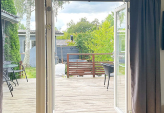 Uitzicht vanuit huis op een houten terras met tuinmeubelen bij een lodge in Gränna, Zweden.