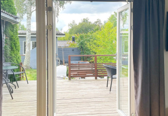 View from inside toward a wooden deck with outdoor furniture at a lodge in Gränna, Sweden.