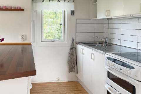 Moderne witte keuken met oven, spoelbak en houten werkblad in een vakantiehuis in Gränna, Zweden.