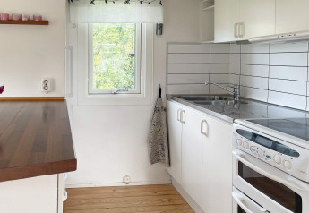 Moderna cucina bianca con forno, lavello e piano in legno in una casa vacanze a Gränna, Svezia.