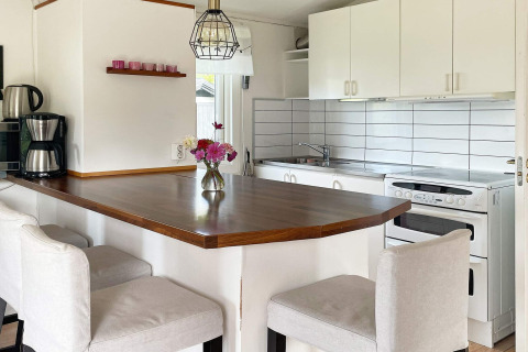 Modernes Ferienhaus-Küche in Gränna, Schweden, mit Tresen, weißen Schränken und Blumen in einer Vase.