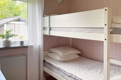 Camera luminosa con letto a castello bianco, carta da parati floreale e finestra in una casa vacanze a Gränna, Svezia.