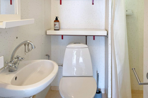 Piccolo bagno con wc bianco, lavandino, mensola e sapone in un alloggio vacanze a Gränna, Svezia.
