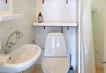 Piccolo bagno con wc bianco, lavandino, mensola e sapone in un alloggio vacanze a Gränna, Svezia.
