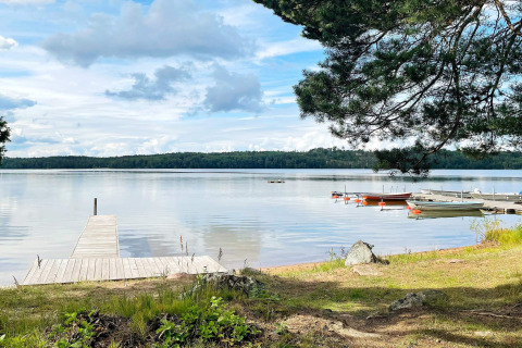 Houten steiger aan een rustig meer met boten en bos op de achtergrond, bij een lodge in Gränna, Zweden.