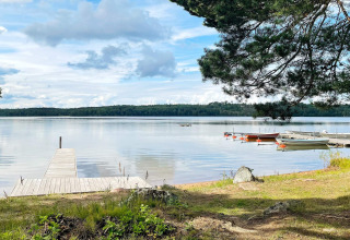 Houten steiger aan een rustig meer met boten en bos op de achtergrond, bij een lodge in Gränna, Zweden.