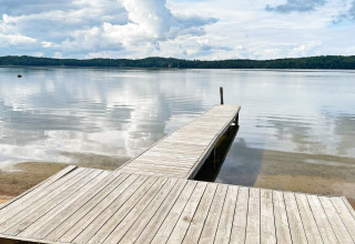 Molo in legno su un lago tranquillo con bosco sullo sfondo vicino a casa vacanze 6 persone a Gränna, Svezia.