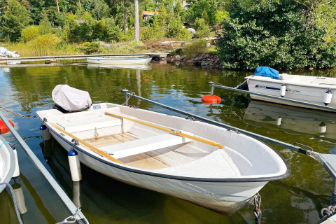 Ein kleines Ruderboot liegt an einem Steg an einem ruhigen See beim 6-Personen-Ferienhaus in Gränna, Schweden.
