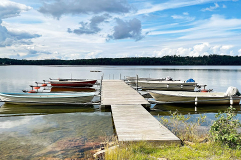 Houten steiger met aangemeerde boten bij een rustig meer bij 6-persoons vakantiehuis in GRÄNNA, Zweden.