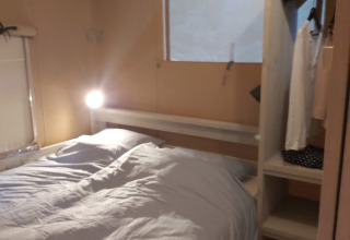 Interieur van een Ranger Lodge safaritent bij Petite Suisse in België, met een bed, kast en een raam.