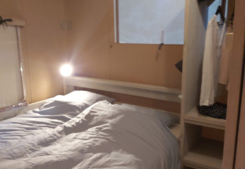 Interno di una tenda safari Ranger Lodge a Petite Suisse, Belgio, con letto matrimoniale, armadio e finestra.