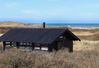 Ferienhaus für 4 Personen in Bindslev, Dänemark, mit schwarzem Dach und Meerblick über Dünen.