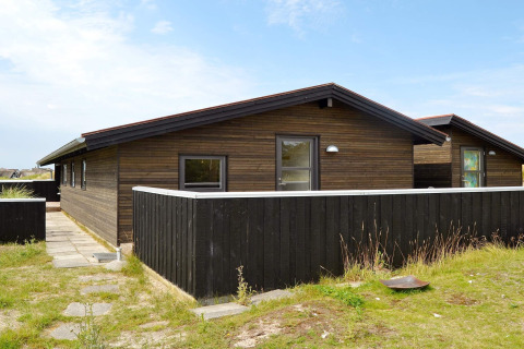 Casa vacanze moderna per 6 persone a Fanø, Danimarca, con rivestimento in legno e recinzione nera.