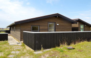 Casa de vacaciones moderna para 6 personas en Fanø, Dinamarca, con revestimiento de madera y cerca negra.