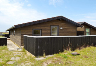Casa vacanze moderna per 6 persone a Fanø, Danimarca, con rivestimento in legno e recinzione nera.