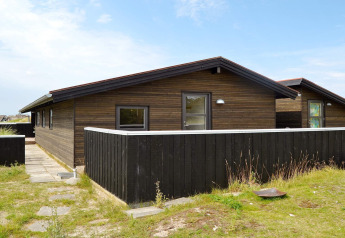 Maison de vacances moderne pour 6 personnes à Fanø, Danemark, avec bardage bois et clôture noire.