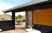 Terrasse en bois avec mobilier extérieur au gîte 6 personnes à Fanø, Danemark, vue sur la nature.