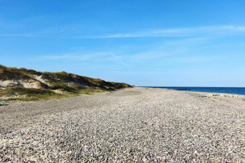 Spiaggia di ciottoli e dune sotto cielo azzurro vicino alla casa '6 person holiday home in Fanø', Danimarca.