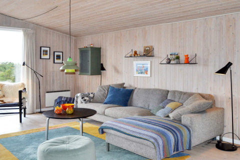 Gemütliches Wohnzimmer in einem Ferienhaus in Fanø, Dänemark, mit grauem Sofa und bunter Dekoration.