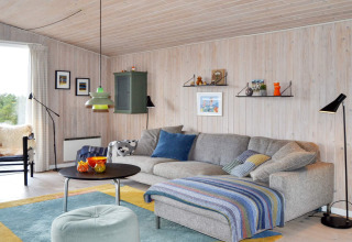 Gemütliches Wohnzimmer in einem Ferienhaus in Fanø, Dänemark, mit grauem Sofa und bunter Dekoration.