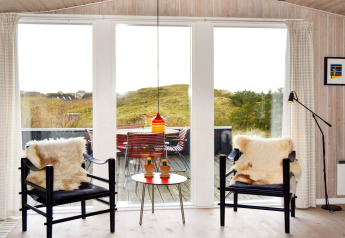 Lichte woonkamer in 6-persoons vakantiehuis op Fanø, Denemarken met grote ramen, uitzicht en comfortabele stoelen.