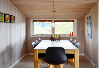 Comedor del alojamiento para 6 personas en Fanø, Dinamarca, con sillas negras modernas y decoración colorida.