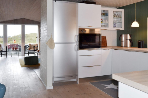Moderne Küche mit weißen Schränken, Ofen und Kühlschrank in einer Ferienhütte in Fanø, Dänemark.